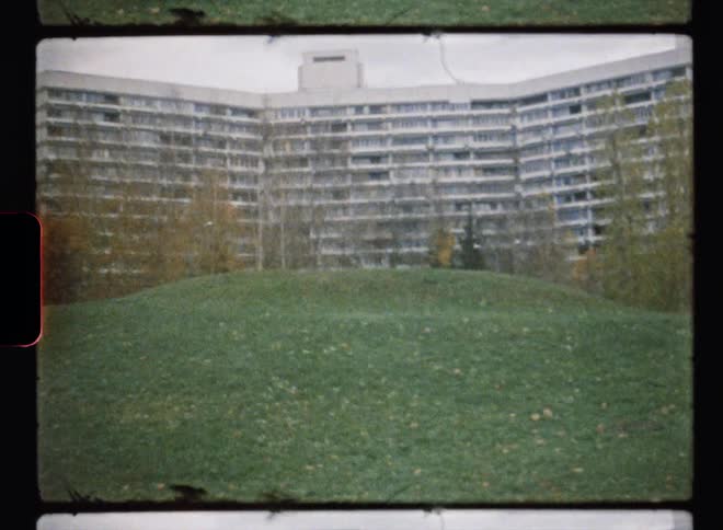 A hilly field outside a large building on a cloudy day