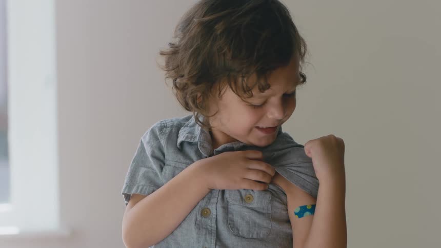 Young boy shows off his bandaid after getting vaccinated