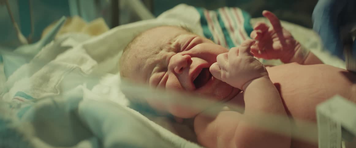 Nurse with gloves measures newborn baby in incubator