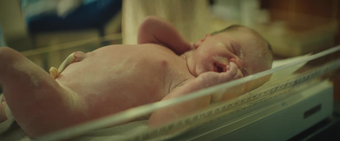 Doctor wearing blue latex gloves picks up a newborn baby in the hospital