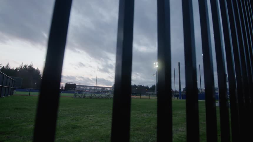 A fence is surrounding the sports field at dusk