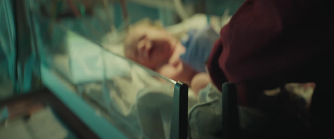 Nurse tends to baby lying in bassinet in hospital nursery