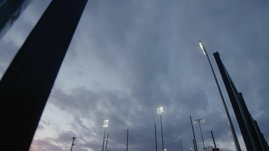 Stadium lights glowing under a cloudy sky at dusk