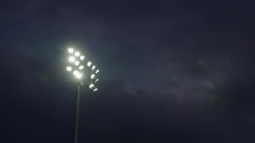 Bright football stadium high mast light beams at night