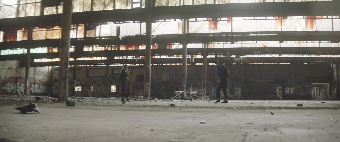A man is taking pictures of a woman near an abandoned building