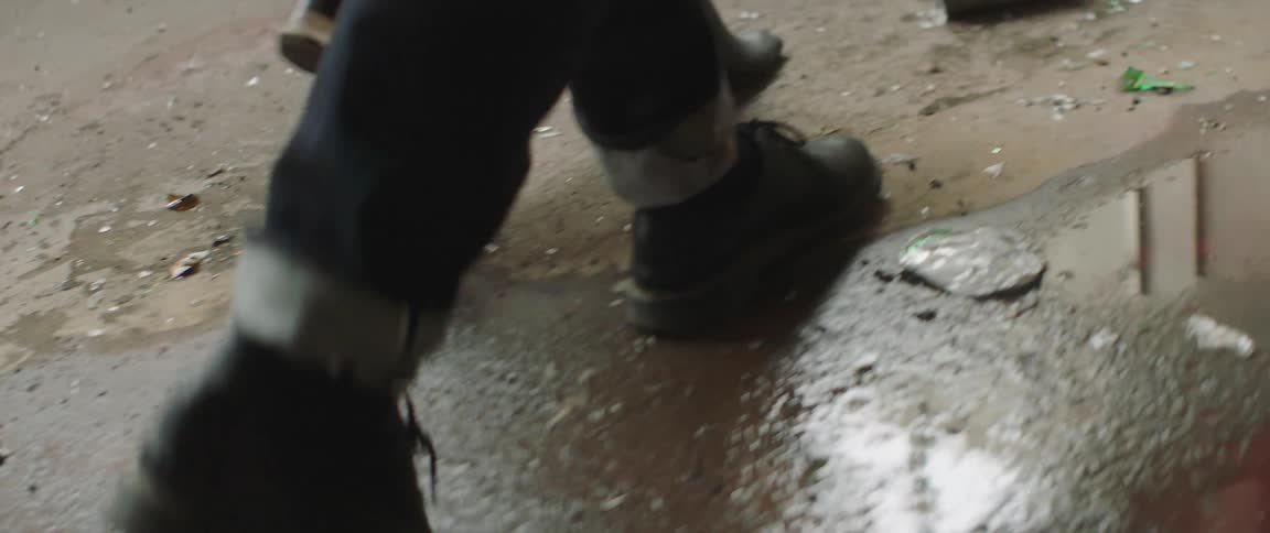 A man and woman walk through a puddle in a parking lot