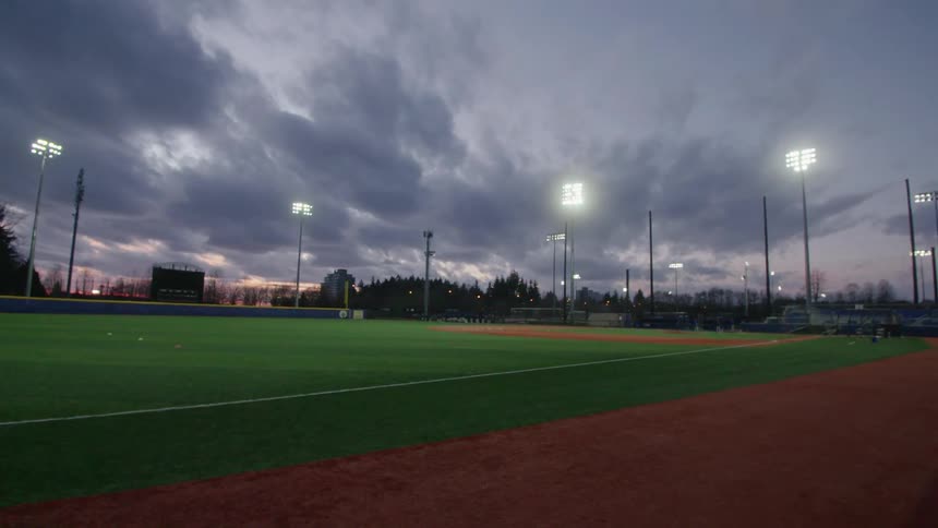 An empty sports field is displayed at dusk