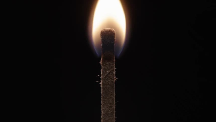Somebody uses a lighter to light a match in the darkness