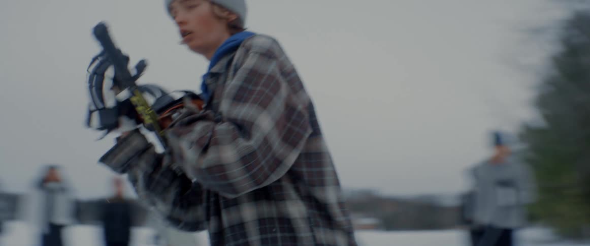 Teenaged boy puts on hockey gloves then gets in position to play hockey outdoors in the winter