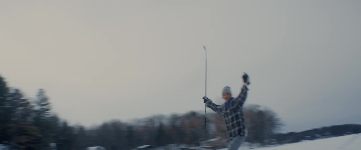 A man raises his arms in celebration after scoring a goal playing ice hockey on a lake