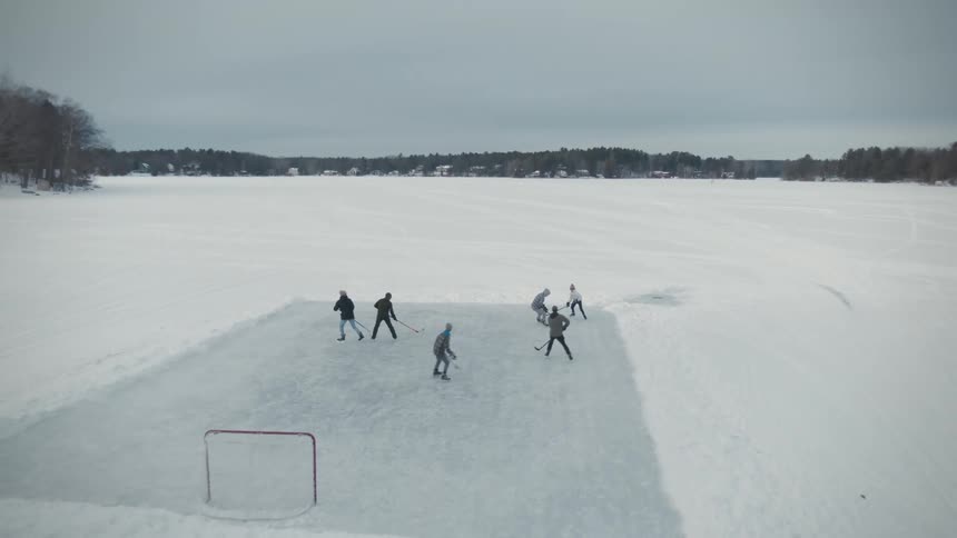 A group of people are outside playing hockey on a winter day