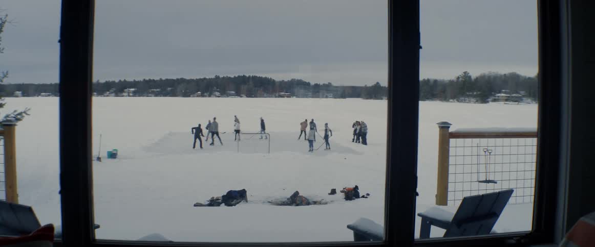 People are playing hockey on the frozen lake out the window