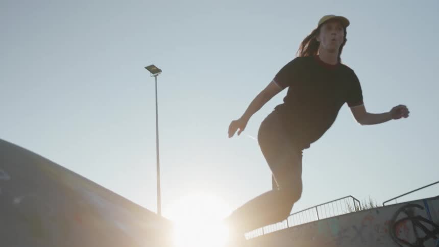 A girl is skateboarding on ramps outdoors at dusk