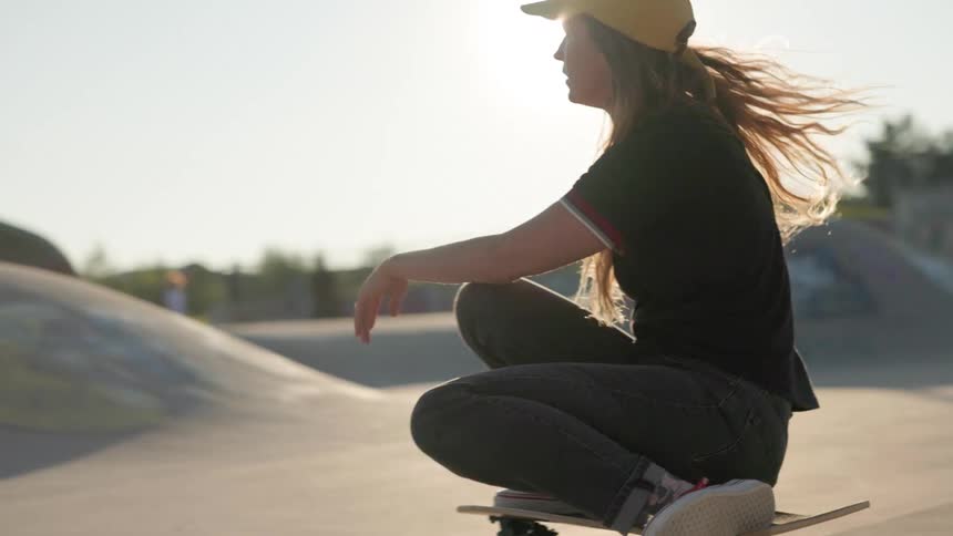 A girl is skate boarding at a park during dusk