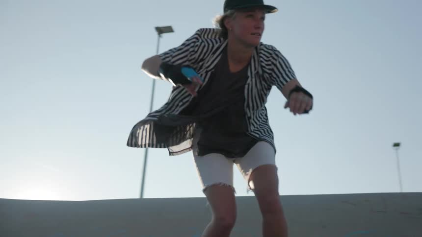 Young person wearing a baseball cap doing a skateboarding trick on a skateboard park outdoors on a sunny day
