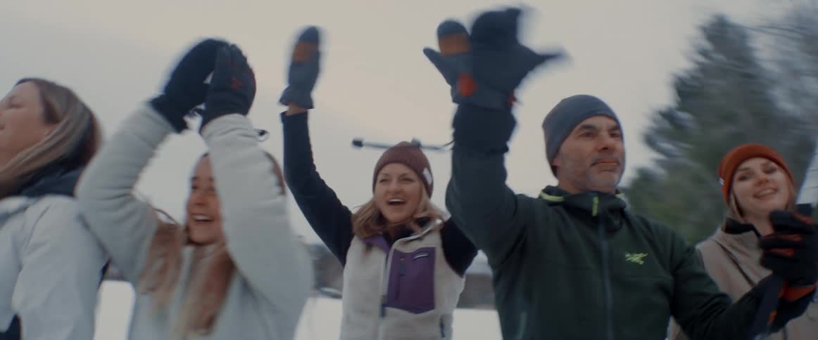 A group of people cheer during an ice hockey game outdoors