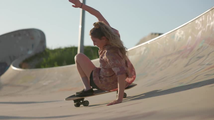 Young woman doing a skateboarding trick on a skate park outdoors on a sunny day