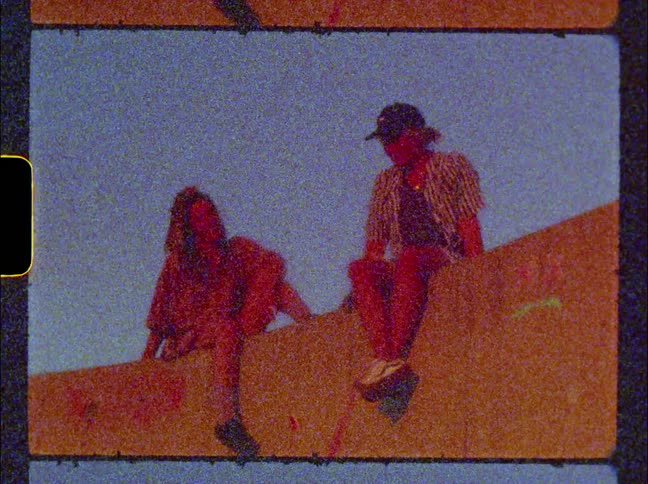 Two women are sitting on a wall hanging out on a clear day