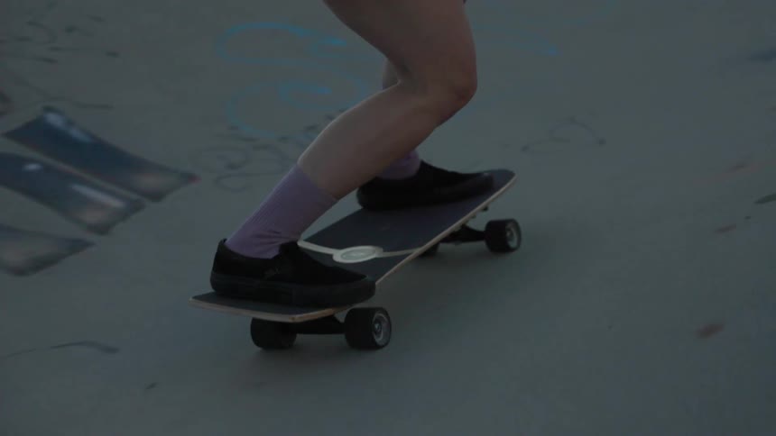 A skateboarder wearing cutoff denim shorts skates at a park on a sunny day