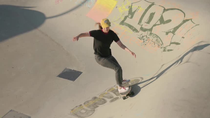 Young woman doing a skateboarding trick on a skate park outdoors on a sunny day