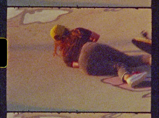 A girl is riding a skateboard and she falls and then grabs her skateboard and gets up