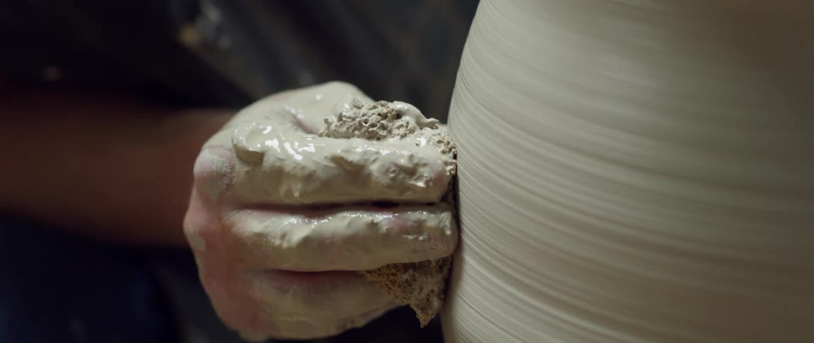 Potter smooths clay vessel spinning on wheel