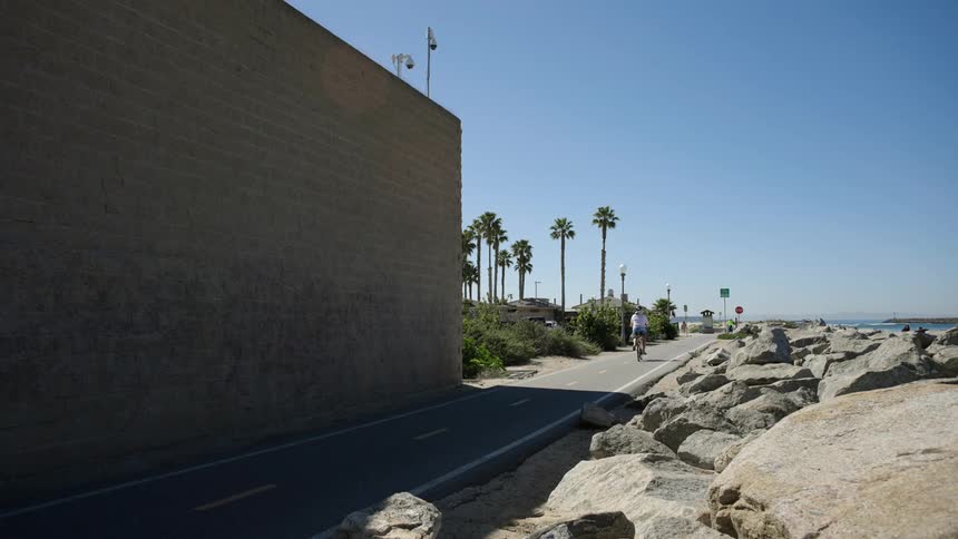 A man rides his bike on the trail by the beach