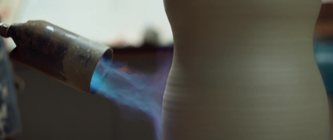 Potter uses torch flame on outside of pottery vessel