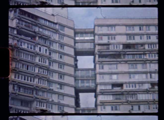 Film footage of a tall building is displayed during the day