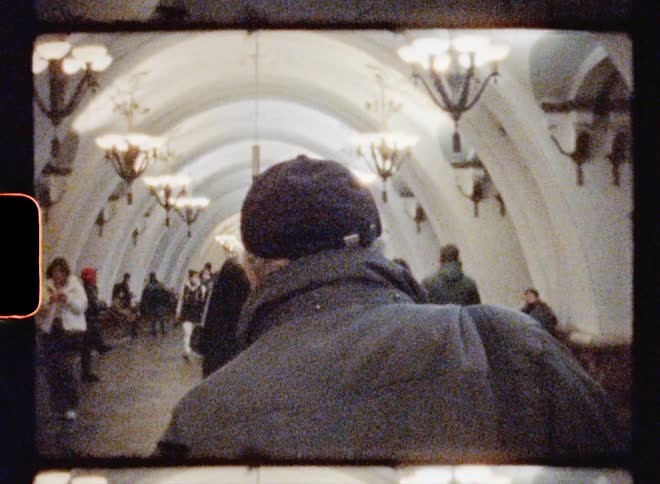 Man wearing a cap walks through a tunnel with other pedestrians