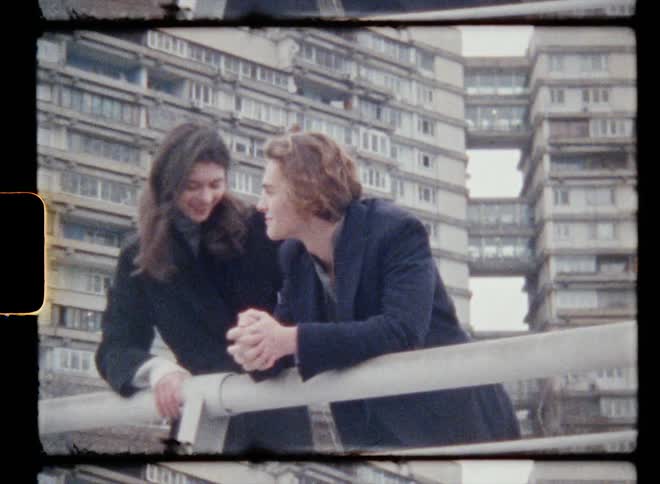 A woman teases her boyfriend by sitting on the railing but he pulls her back down to him