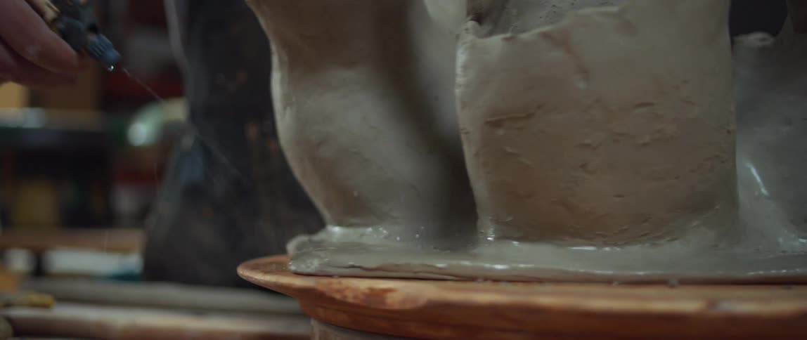 Sculptor uses sprays water over a clay sculpture over a turntable