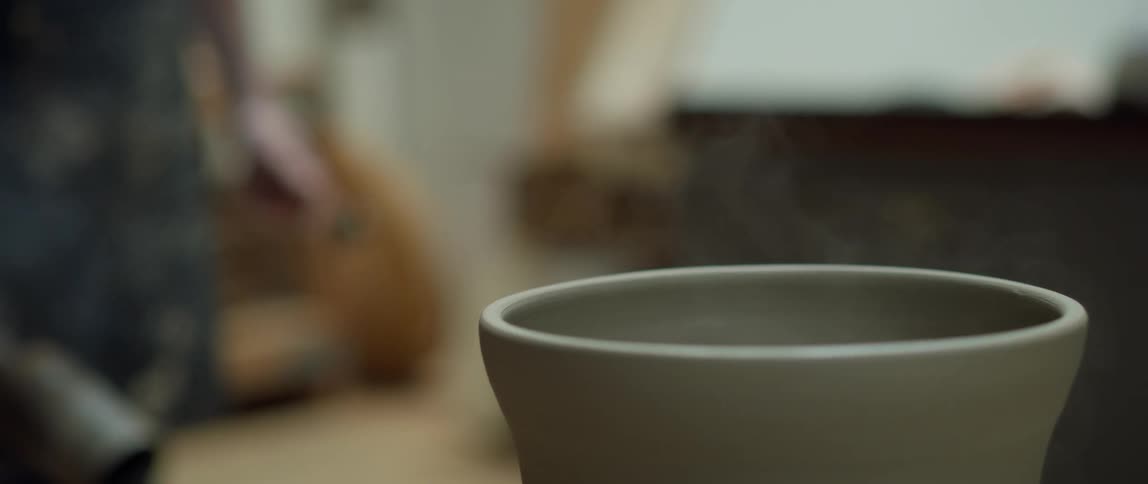 Potter bakes clay vessel with torch then puts torch down as smoke rises from the clay