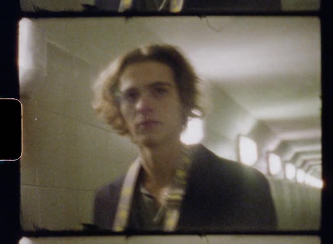 A man walking through a tunnel with lights on the wall