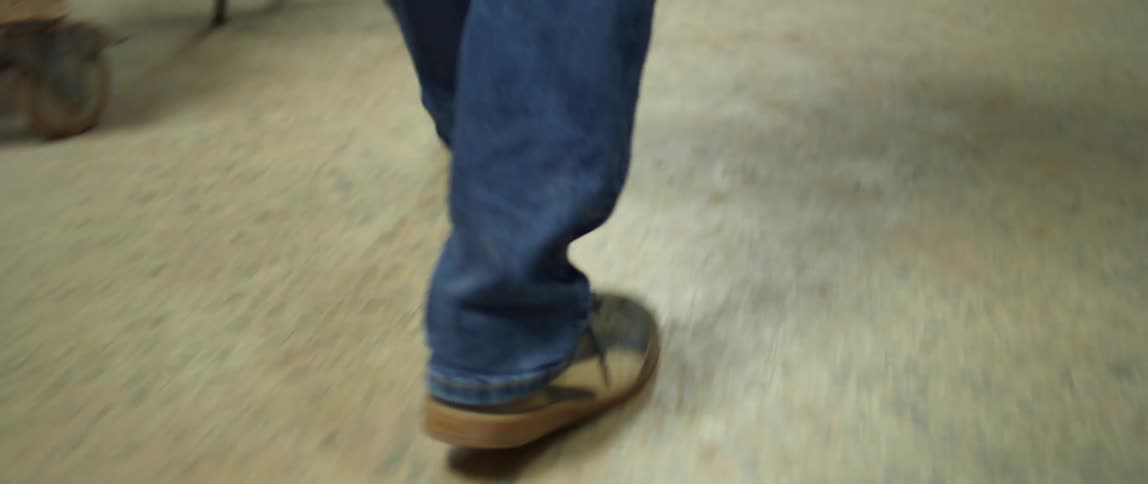 A man walks down some stairs and towards some chairs