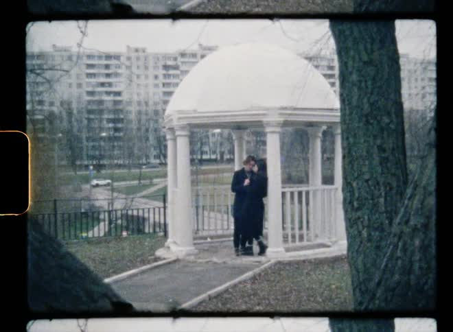 A man steps closer and clasps hands with a woman in a gazebo