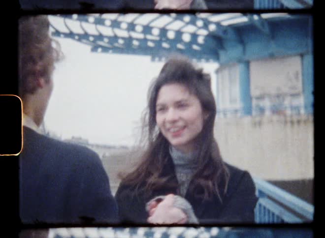 Young couple holding hands walking up the stairs of a structure in the city caught on vintage film