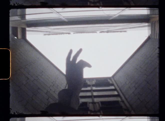 A man is raising his hand toward the sky in an enclosed area