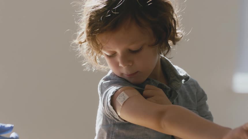 A doctor draws on the bandage on kids arm