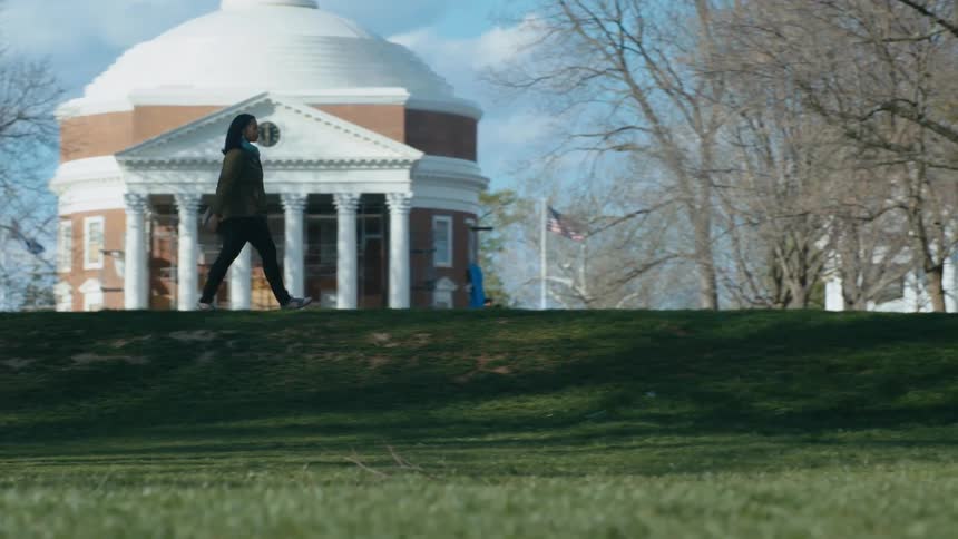 Woman walks along walkway past landmark buildings