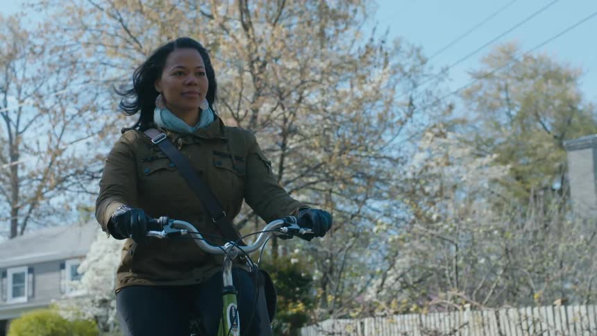 A woman riding a bicycle through a neighborhood