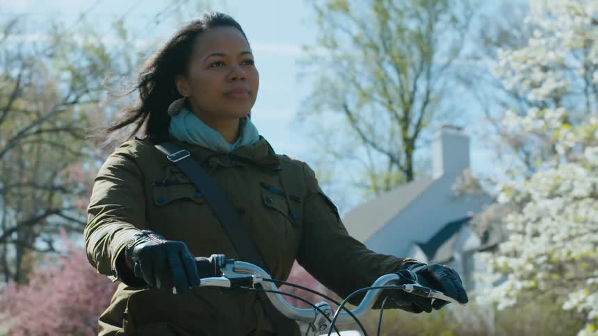 A woman riding her bike through a neighborhood in spring