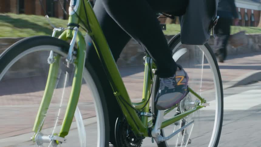 A woman riding her bicycle on campus in the morning