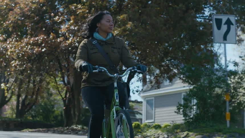 Woman rides bicycle through neighborhood