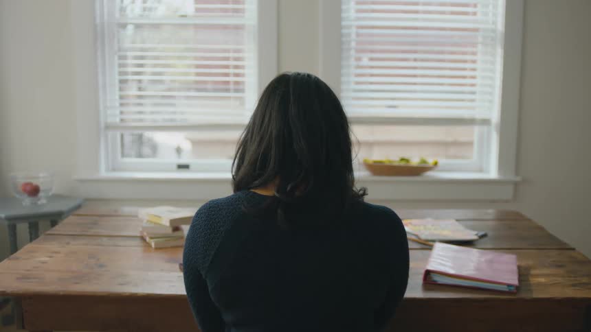 A woman is sitting at a table indoors