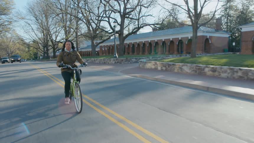 A woman riding a bicycle down a road in the fall