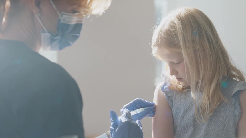 Female nurse gives vaccine to a young girl