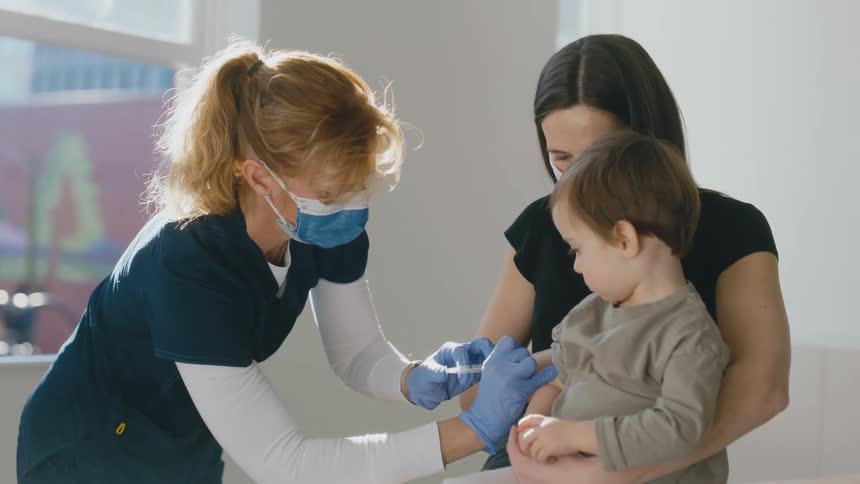 A nurse vaccinates a child with his mother by his side