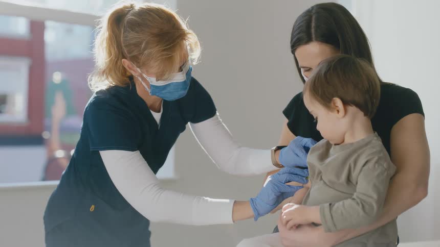 Nurse places a bandage on arm of a little boy after vaccination