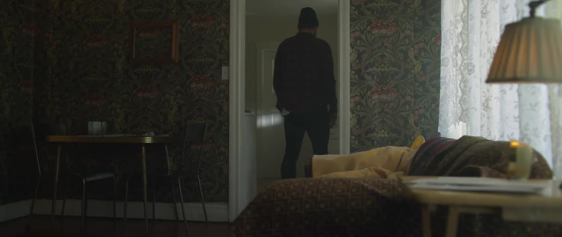 Man wearing a toque pauses as he walks through a doorway in the living room then continues on
